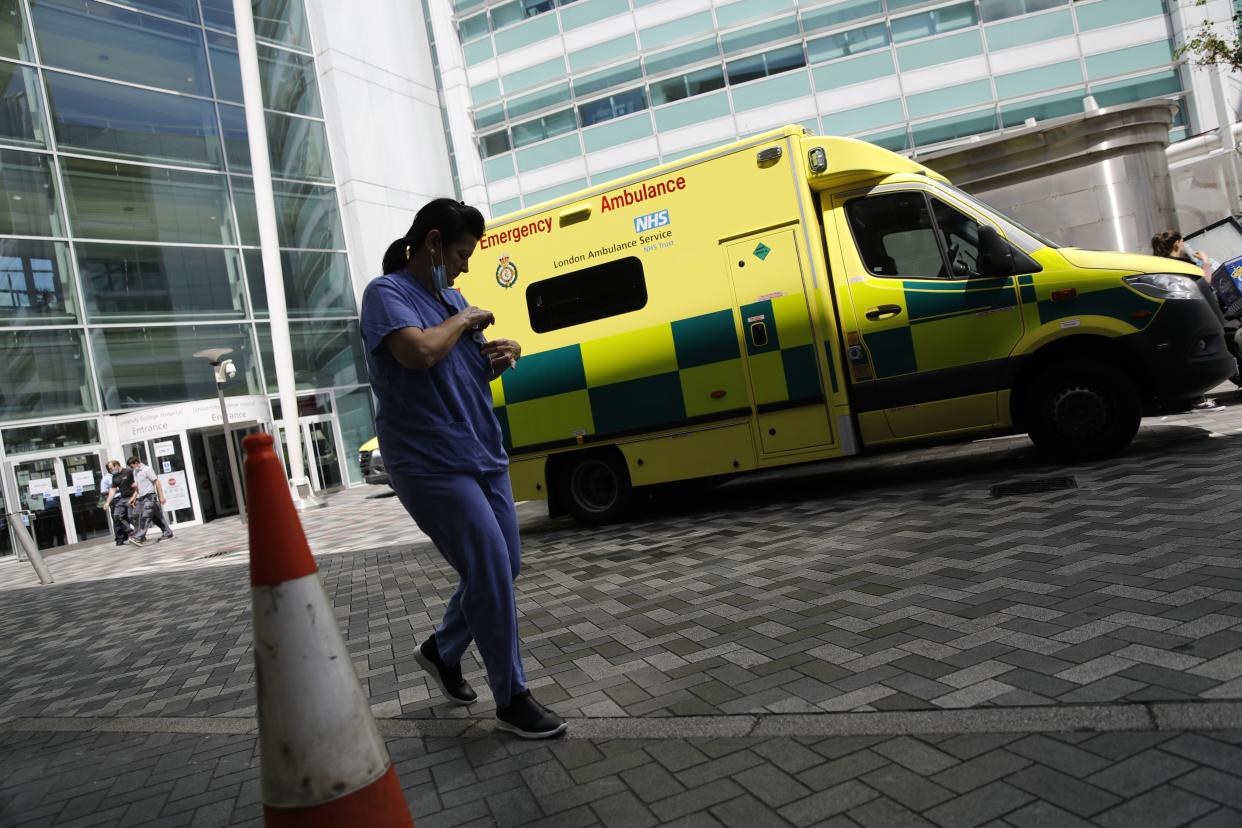 A member of clinical staff walks past an ambulance at University College Hospital in London on July 17, 2020. - Boris Johnson said on July 17 he hoped Britain would "return to normality" by November despite being badly affected by the coronavirus and predictions of a second wave of cases during winter months. Johnson announced that to prepare for a possible winter spike in cases the state-run National Health Service (NHS) would receive an extra £3 billion ($3.8 billion, 3.3 million euros). (Photo by Tolga AKMEN / AFP) (Photo by TOLGA AKMEN/AFP via Getty Images)