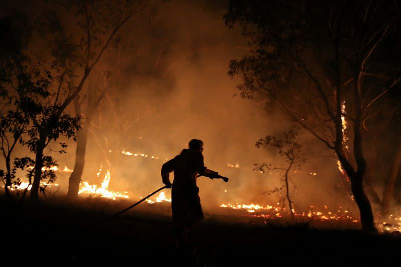 A firefighter works to extinguish flames after a bushfire burnt through the area in Bredbo