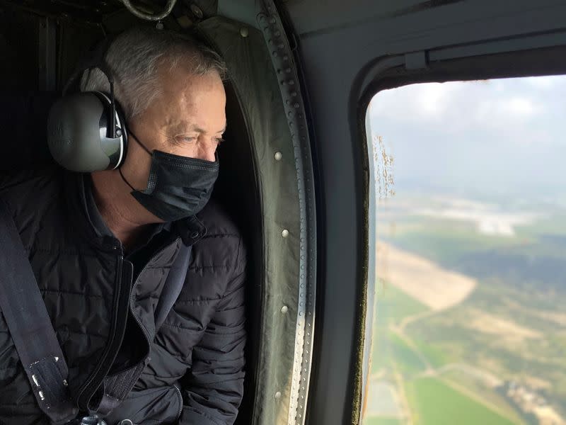 Israeli Defence Minister Benny Gantz wears a face mask as he looks out from the window of a helicopter during a tour of the Gaza border area, southern Israel