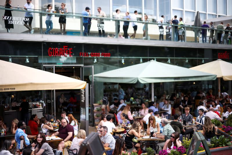 FILE PHOTO: People sit at an outdoor restaurant on the South Bank during sunny weather, amid the coronavirus disease (COVID-19) outbreak, in London