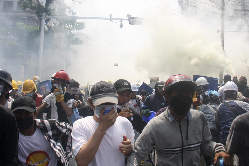 CORRECTS CITY TO YANGON INSTEAD OF MANDALAY - Protesters run away from tear gas launched by security forces during an anti-coup protest in Yangon, Myanmar, Tuesday, March 2, 2021. Demonstrators in Myanmar took to the streets again on Tuesday to protest last month’s seizure of power by the military, as foreign ministers from Southeast Asian countries prepared to meet to discuss the political crisis. (AP Photo)