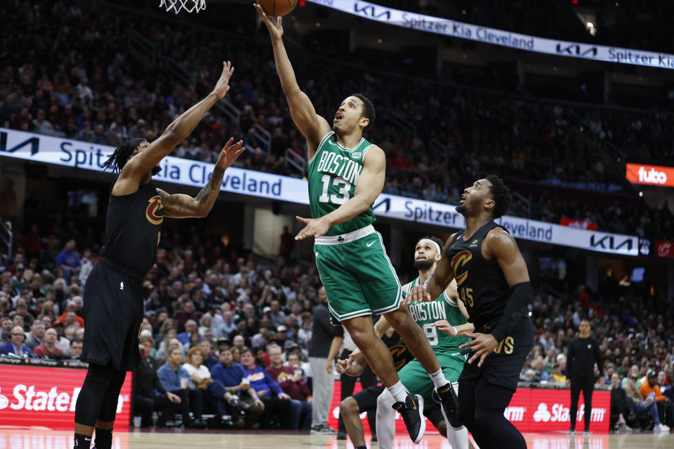 Boston Celtics guard Malcolm Brogdon (13) shoots against Cleveland Cavaliers forward Lamar Stevens and guard Donovan Mitchell (45) during the second half of an NBA basketball game, Monday, March 6, 2023, in Cleveland. (AP Photo/Ron Schwane)