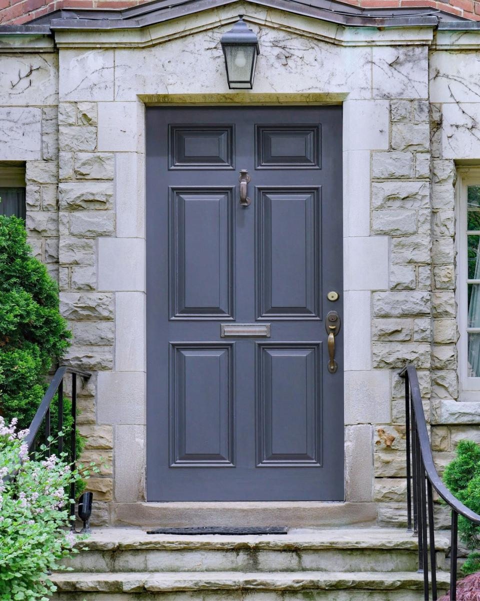 Grey Front door of stone faced house surrounded by cedar bushes