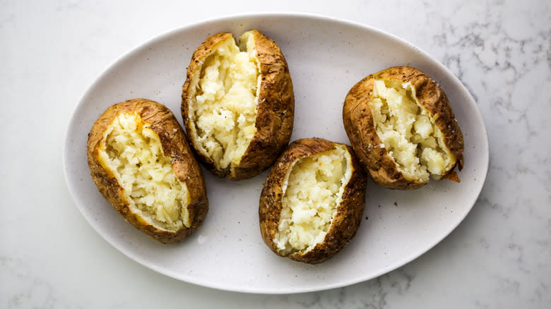 fluffed baked potatoes cut open on plate