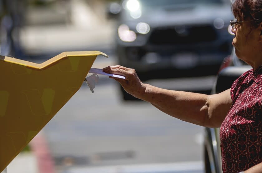 NORWALK, CA - JUNE 6, 2022: An LA County voter puts her ballot in the dropbox the day before Election Day at the LA County Registrar-Recorder on June 6, 2022 in Norwalk, California.(Gina Ferazzi / Los Angeles Times)