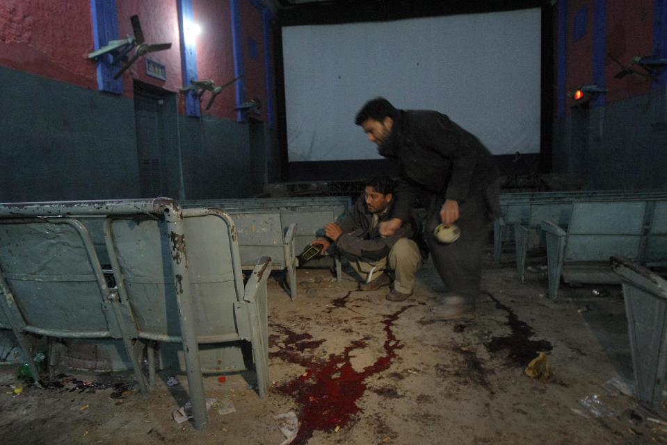 In this Sunday, Feb. 2, 2014 photo, plainclothes Pakistani police officers examine the site of a grenade attack inside a movie theater in Peshawar, Pakistan. The Pakistani government has recently opened negotiations with domestic militants called the Pakistani Taliban designed to end years of fighting in the northwest that has cost thousands of lives and forced hundreds of thousands of people to flee their homes. (AP Photo/Mohammad Sajjad)