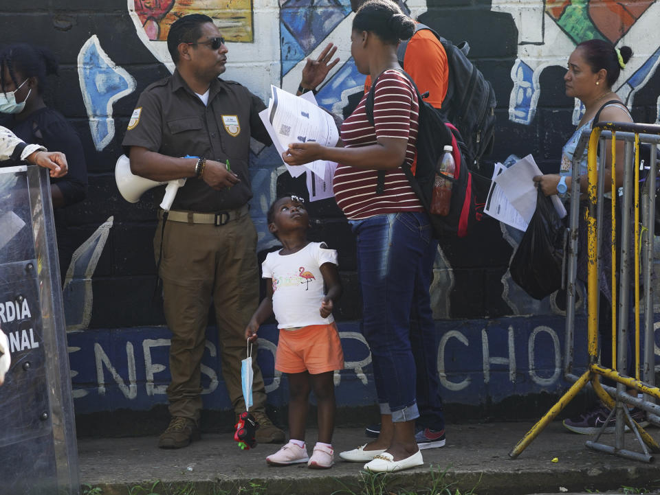 A Mexican immigration officer checks the documents of migrants waiting in line to apply for legal migration papers outside the National Migration Institute in Tapachula, Chiapas state, Mexico, Tuesday, Oct. 4, 2022. Many migrants travel through Mexico using “safe passage” permits, the common term for some of the temporary documents issued by the Mexican government. (AP Photo/Marco Ugarte)