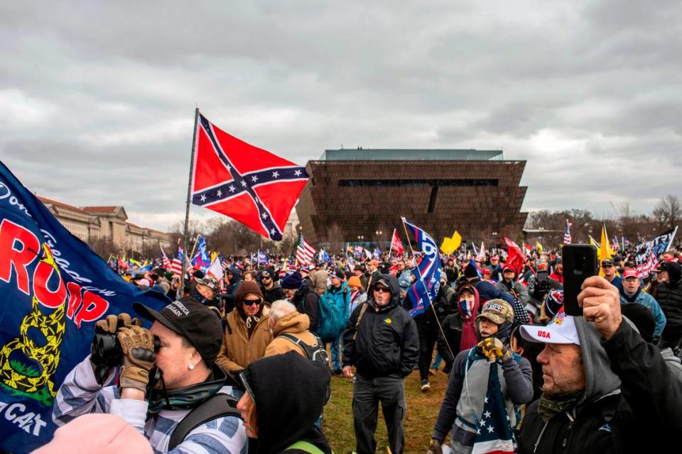 Un hombre enarbola la bandera confederada, con el Museo Nacional de Historia y Cultura Afroestadounidense de fondo, mientras el presidente Donald Trump se dirige a la multitud en Washington, el 6 de enero de 2021.