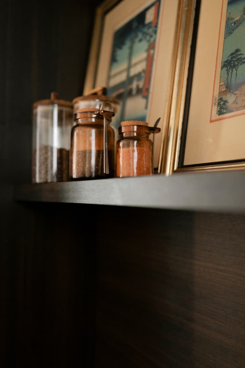 Dark wood floating shelf with spice jars and art