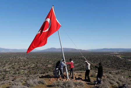 Villagers fix a broken flagpole in Sugedigi village on the Turkish-Syrian border in Hatay province, Turkey January 20, 2018. REUTERS/Osman Orsal