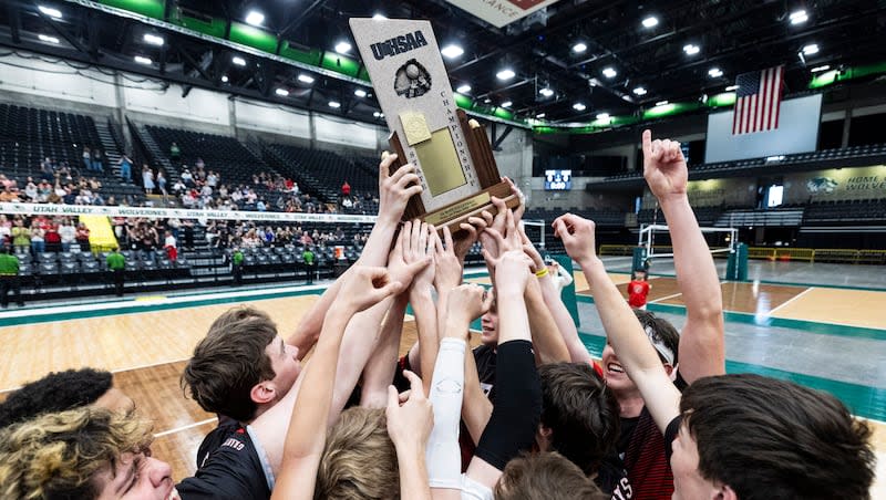 Grantsville players surround the championship trophy after defeating North Sanpete in the 3A boys volleyball state championship held at the UCCU Center in Orem on Saturday, May 11, 2024.