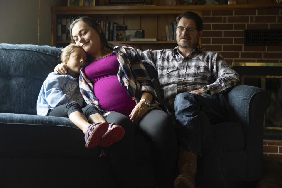 Alisha Alderson and her husband, Shane, sit with their daughter Adeline, 5, in the living room of their house in Baker City, Ore., on Tuesday, Sept. 5, 2023. Shane is Baker County's chief commission chair and Alisha is expecting their daughter, Ava, in September. Because of the closing of Baker City's only obstetrical unit, the family is traveling to the Boise, Idaho area, a little over 100 miles away, to give birth. (AP Photo/Kyle Green)