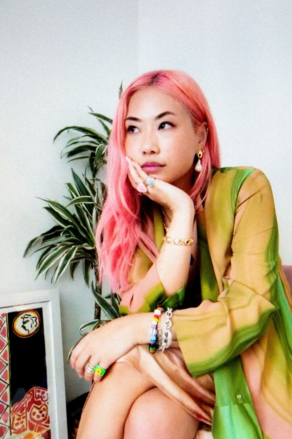 designer jessica tse of notte wears a green jacket and colorful jewelry and has long pink hair