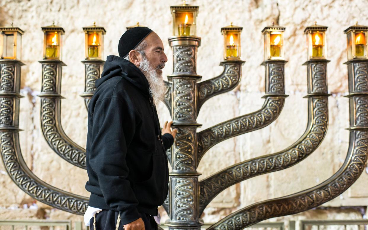 A man next to a menorah at the Western Wall in Jerusalem on the seventh day of Hanukkah - Copyright (c) 2014 Rex Features. No use without permission.