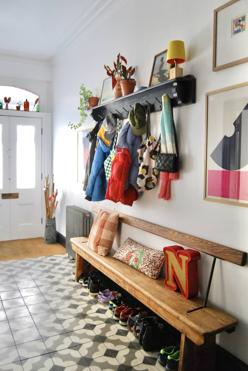 Entryway with wooden bench and large coach rack.