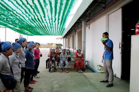 A supervisor of a sewing team gives workers instructions before they start their shift at Complete Honour Footwear Industrial, a footwear factory owned by a Taiwan company, in Kampong Speu, Cambodia, July 5, 2018. REUTERS/Ann Wang