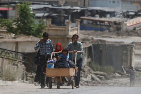 A displaced Iraqi pushes a wheelbarrow with children on their way home after the end of the battles between the Iraqi forces and Islamic State militants at their district in western Mosul, Iraq, April 30, 2017. REUTERS/Muhammad Hamed