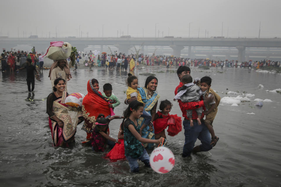 An Indian Hindu family walks on the shallow banks of the Yamuna river, covered with chemical foam caused by industrial and domestic pollution, during Chhath Puja festival in New Delhi, India, Saturday, Nov. 2, 2019. Despite the river being accorded the status of a living human entity by an Indian court, untreated sewage and industrial pollutants have turned it into one of the most polluted rivers in the world. The river Yamuna is one of the major tributaries of the Ganges. (AP Photo/Altaf Qadri)