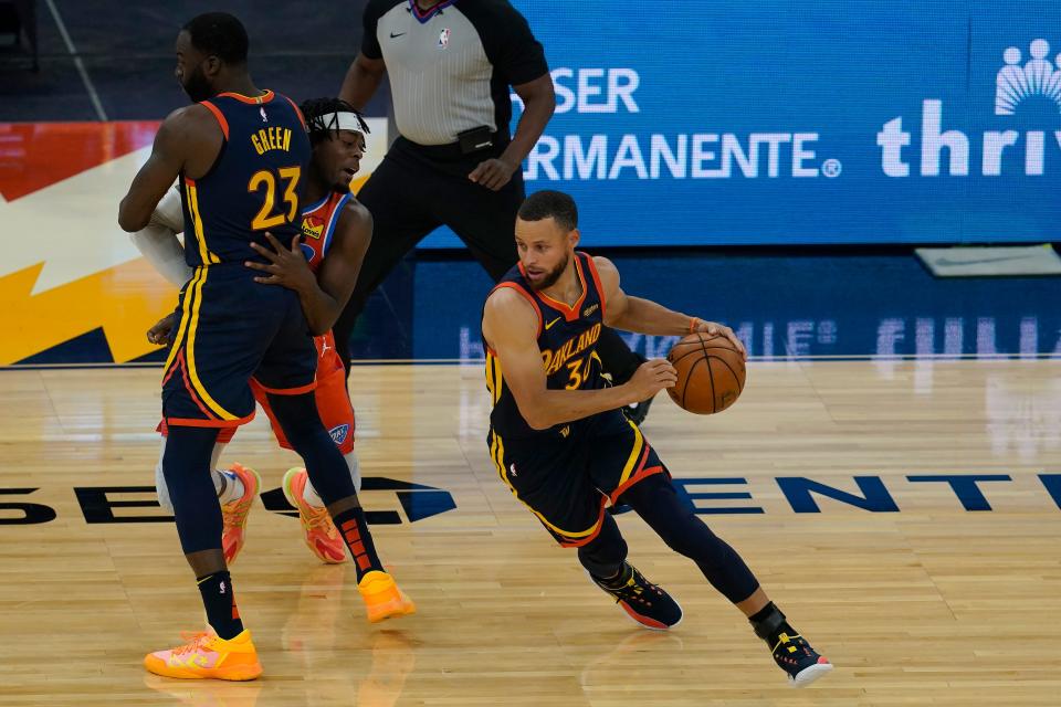 Warriors guard Stephen Curry, right, dribbles as forward Draymond Green (23) screens against the Thunder's Luguentz Dort during game in 2021 in San Francisco.