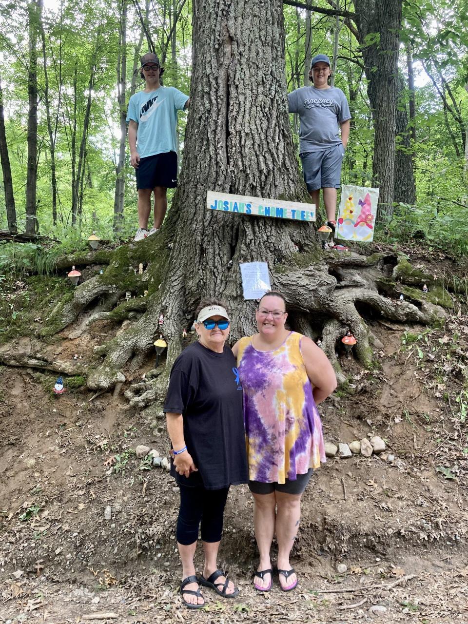 Josiah Moore (top left), his cousin Caleb Northrup (top right), his grandma Georgetta Marnell (bottom left) and his mom Danielle Moore (bottom right) pose in front of Josiah's Gnome Tree on Chambers Road in Pinckney.