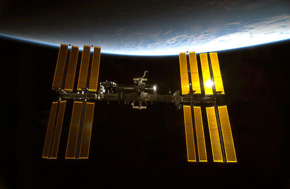 Sunlight glints off the International Space Station with the blue limb of Earth providing a dramatic backdrop in this photo taken by an astronaut on the shuttle Endeavour just before it docked after midnight on Feb. 10, 2010 during the STS-130