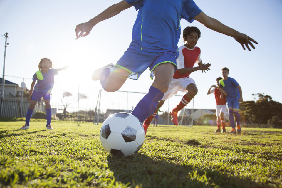 A close up action of boy's soccer teams, aged 12-14, playing a football match. (Photo via Getty Images)