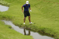 Collin Morikawa fishes his ball out of the creek on the seventh hole during a practice round for the PGA Championship golf tournament, Tuesday, May 17, 2022, in Tulsa, Okla. (AP Photo/Eric Gay)