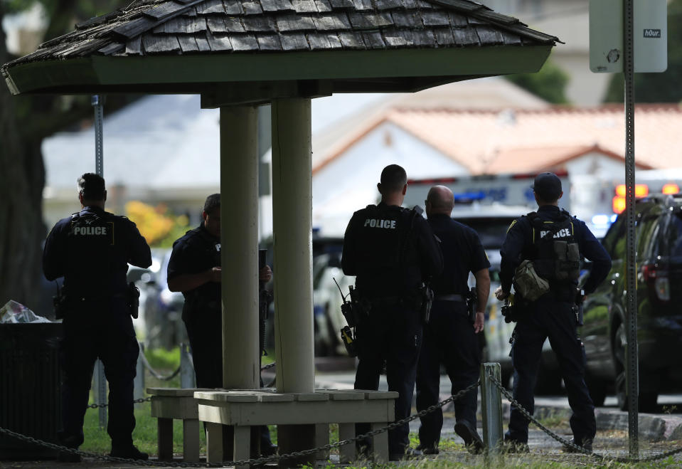 Honolulu police prepare to take defensive positions with their weapons after a shooting and domestic incident at a residence on Hibiscus Road near Diamond Head on Sunday, Jan. 19, 2020, in Honolulu. Witnesses say at least two Honolulu police officers were shot and two civilians were injured. Moments after the shooting, the house was set on fire, possibly by the suspect. (Jamm Aquino/Honolulu Star-Advertiser via AP)