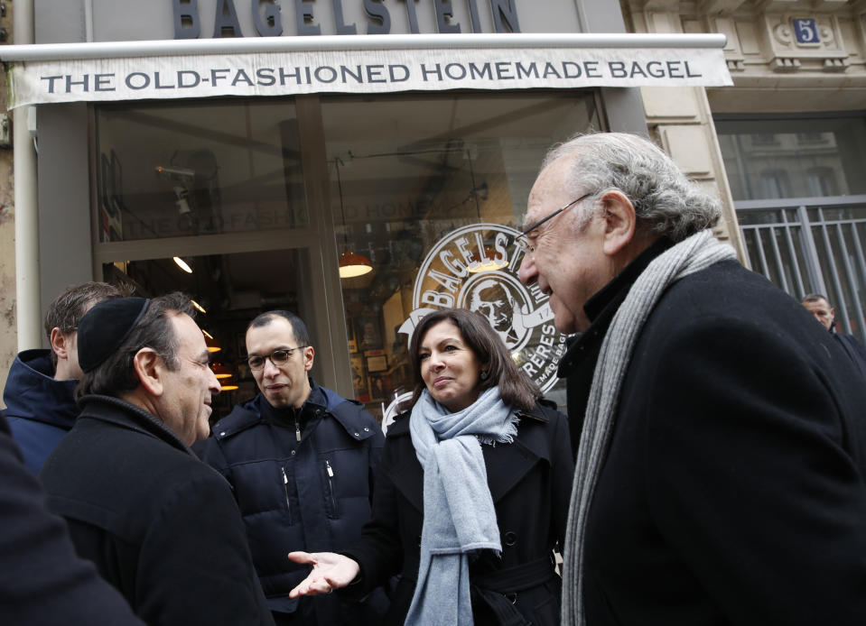 Paris mayor Anne Hidalgo, second right, talks with the President of the Central Jewish Consistory of Paris Joel Mergui, left, as district mayor Pierre Aidenbaum, right, looks on outside the bagel shop which was sprayed with the German word "Juden" on its front window last week, in Paris, Tuesday, Feb.12, 2019. According to French authorities, the total of registered anti-Semitic acts rose to 541 in 2018 from 311 in 2017, a rise of 74 percent. (AP Photo/Christophe Ena)