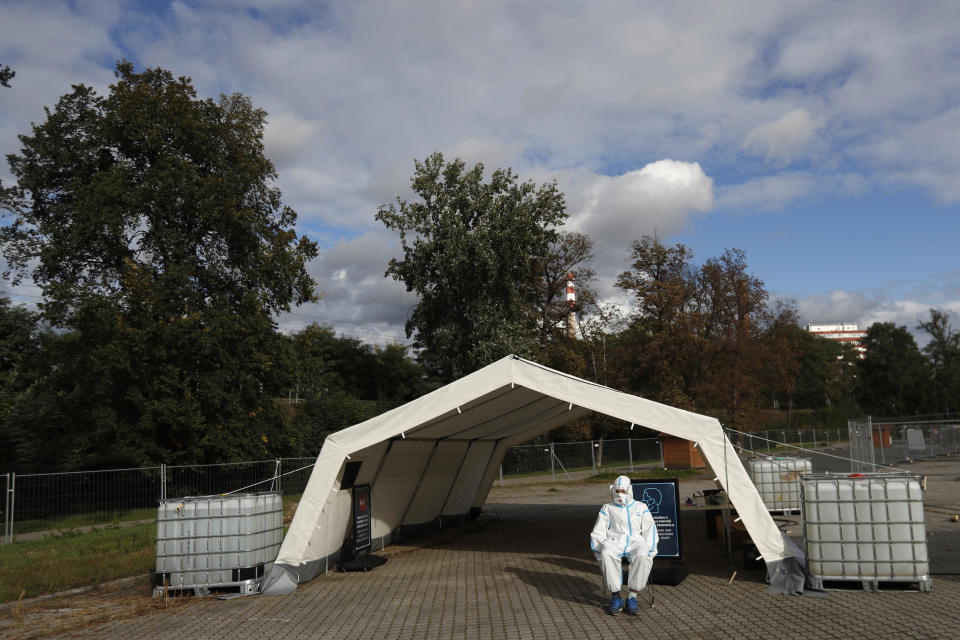 A health care worker in full protective gear, waits to conduct a COVID-19 test at a drive-in sampling station in Prague, Czech Republic, Wednesday, Oct. 7, 2020. Coronavirus infections in the Czech Republic hit a new record high, surpassing 4,000 cases in one day for the first time. (AP Photo/Petr David Josek)