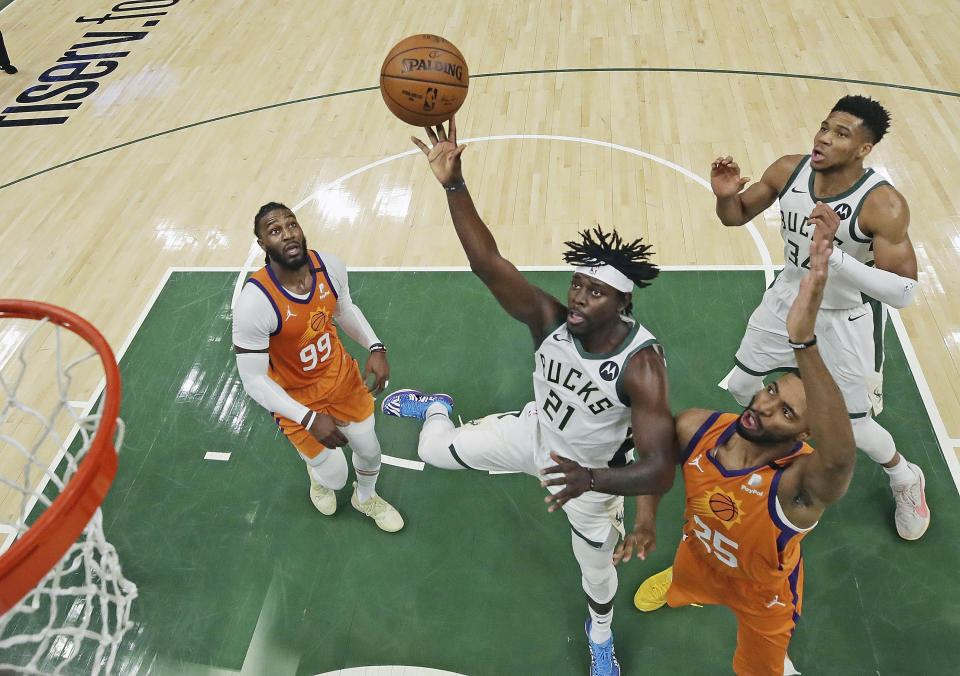 Milwaukee Bucks' Jrue Holiday (21) shoots between Phoenix Suns' Jae Crowder (99) and Mikal Bridges (25) as Bucks' Giannis Antetokounmpo (34) watches during Game 4 of basketball's NBA Finals, Wednesday, July 14, 2021, in Milwaukee. (Jonathan Daniel/Pool Photo via AP)