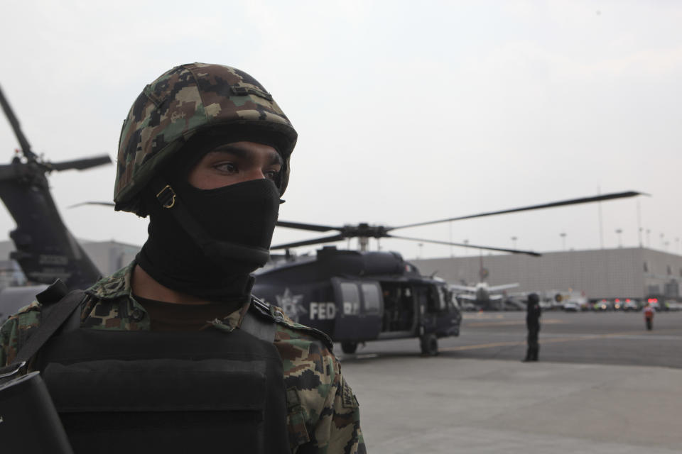 Un infante de la Marina de México monta guardia mientras el helicóptero que transporta al capo del narcotráfico Joaquín "El Chapo" Guzmán se prepara para despegar en un hangar de la Marina en la Ciudad de México el sábado 22 de febrero de 2014. (Foto AP/Marco Ugarte)