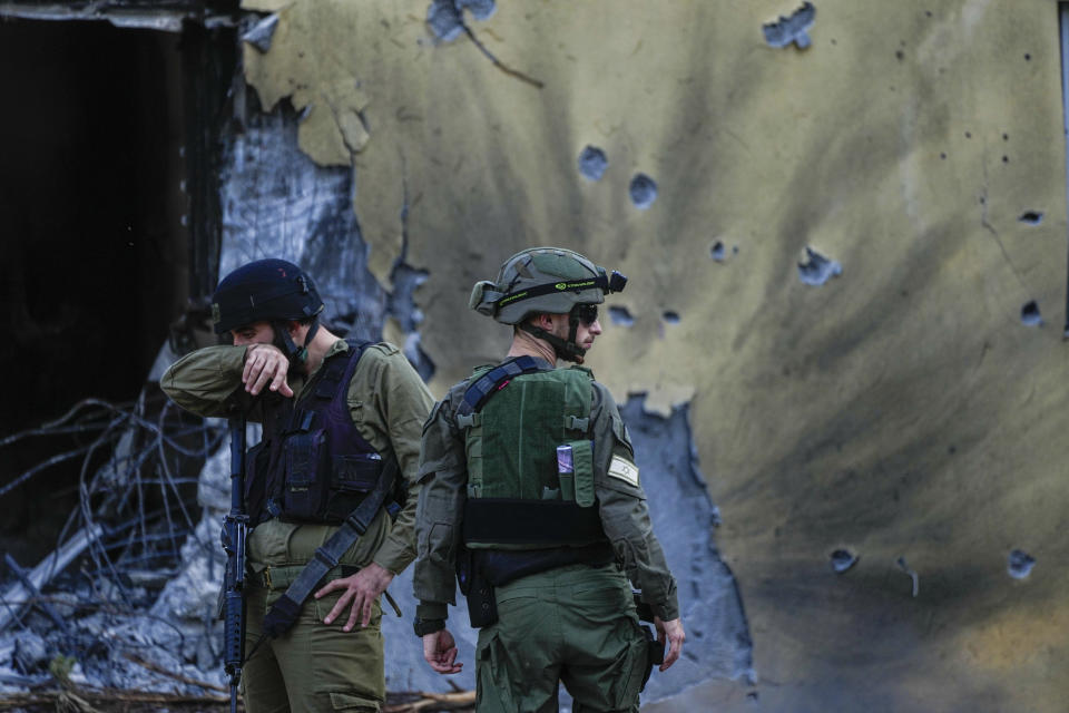 FILE - Israeli soldiers walk past houses destroyed by Hamas militants in Kibbutz Be'eri, Israel, Saturday, Oct. 14, 2023. The Israeli military said Thursday that Israeli hostages held in a home that was struck by tank fire last Oct. 7 were killed by Hamas militants, not Israeli shelling, as it released the results of its first investigation into failures during the deadly attack that triggered the nine-month war in Gaza. (AP Photo/Ariel Schalit, File)