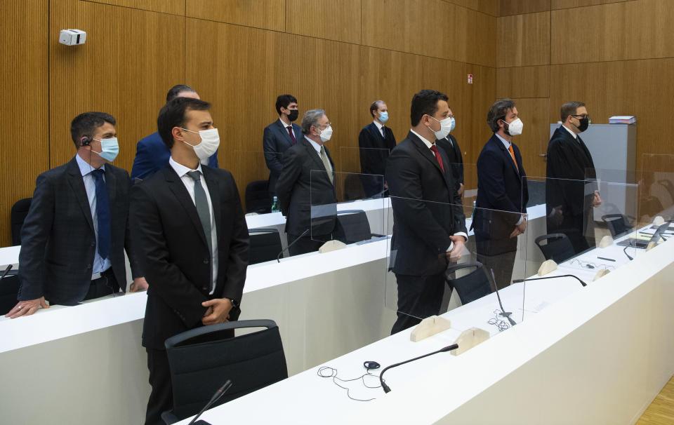 Avimar de Melo Barcelos, back left, mayor of the municipality of Brumadinho, Paulo Richardo Rocha Pinto, husband of a victim, Gustavo Barroso Camara, brother of a victim, lawyer Pedro Martins, and lawyer Jan Erik Spangenberg, left to right, arrive in the courtroom at the Munich Regional Court before the start of the trial in Munich Germany, Tuesday, Sept. 28, 2021. Following the dam disaster in Brumadinho, Brazil, in early 2019, the affected community and the family of one of the 260 fatalities sued TUEV Sued for damages. (Sven Hoppe/dpa via AP)