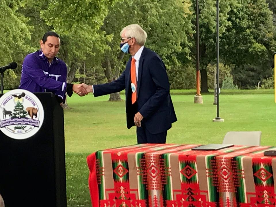 Gov. Tony Evers shakes hands with Oneida Nation Vice Chair Brandon Yellowbird before signing an executive order that officially apologizes for the state of Wisconsin's role in the suffering caused to Indigenous children at boarding schools.