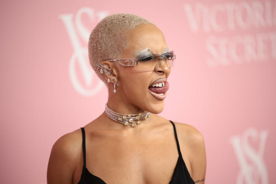 Person in black attire with unique eyewear and earrings, posing at the Victoria's Secret event