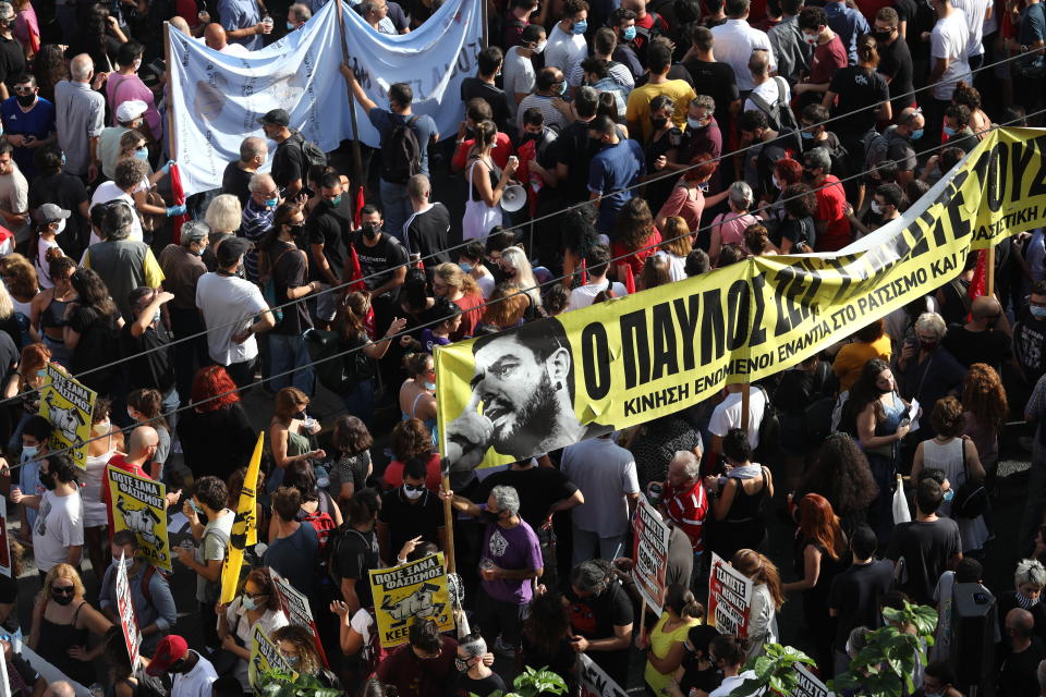 People holding a banner depicting Greek rap singer Pavlos Fyssas, who was stabbed and killed by a supporter of the extreme right Golden Dawn party in 2013, triggering a crackdown on the party, gather for a protest outside a court in Athens, Wednesday, Oct. 7, 2020. The court is to deliver a landmark verdict in the marathon, five-year-long trial against the country's extreme right-wing Golden Dawn party Wednesday, with security tight and anti-fascist rallies outside the court for the politically charged case. (AP Photo/Yorgos Karahalis)