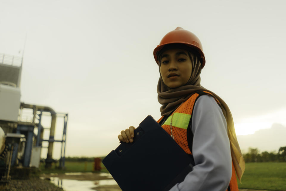 woman wearing a hardhat over her headscarf to work as an engineer