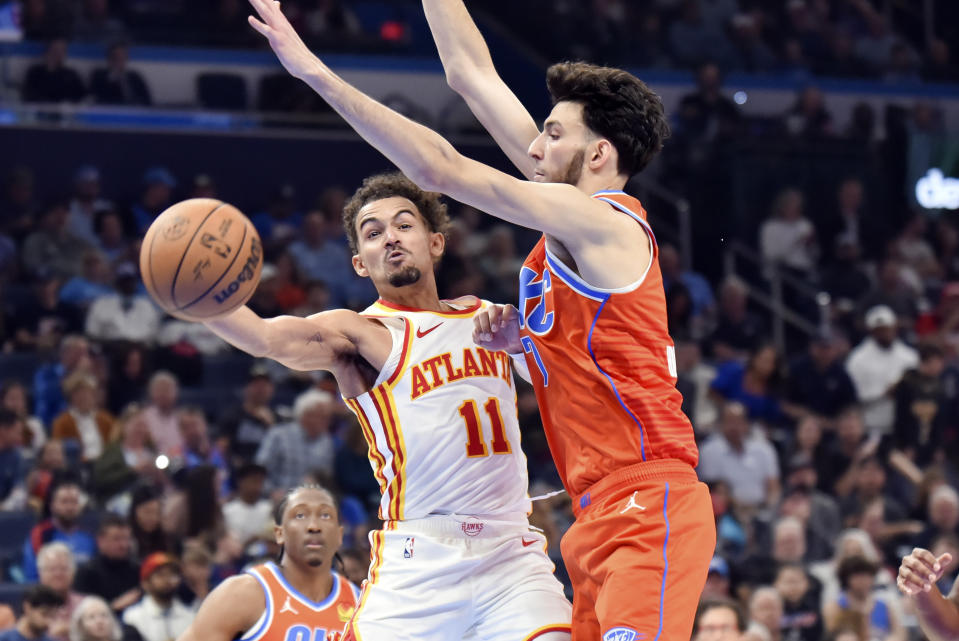 Atlanta Hawks guard Trae Young (11) passes the ball around Oklahoma City Thunder forward Chet Holmgren, right, in the first half of an NBA basketball game, Monday, Nov. 6, 2023, in Oklahoma City. (AP Photo/Kyle Phillips)