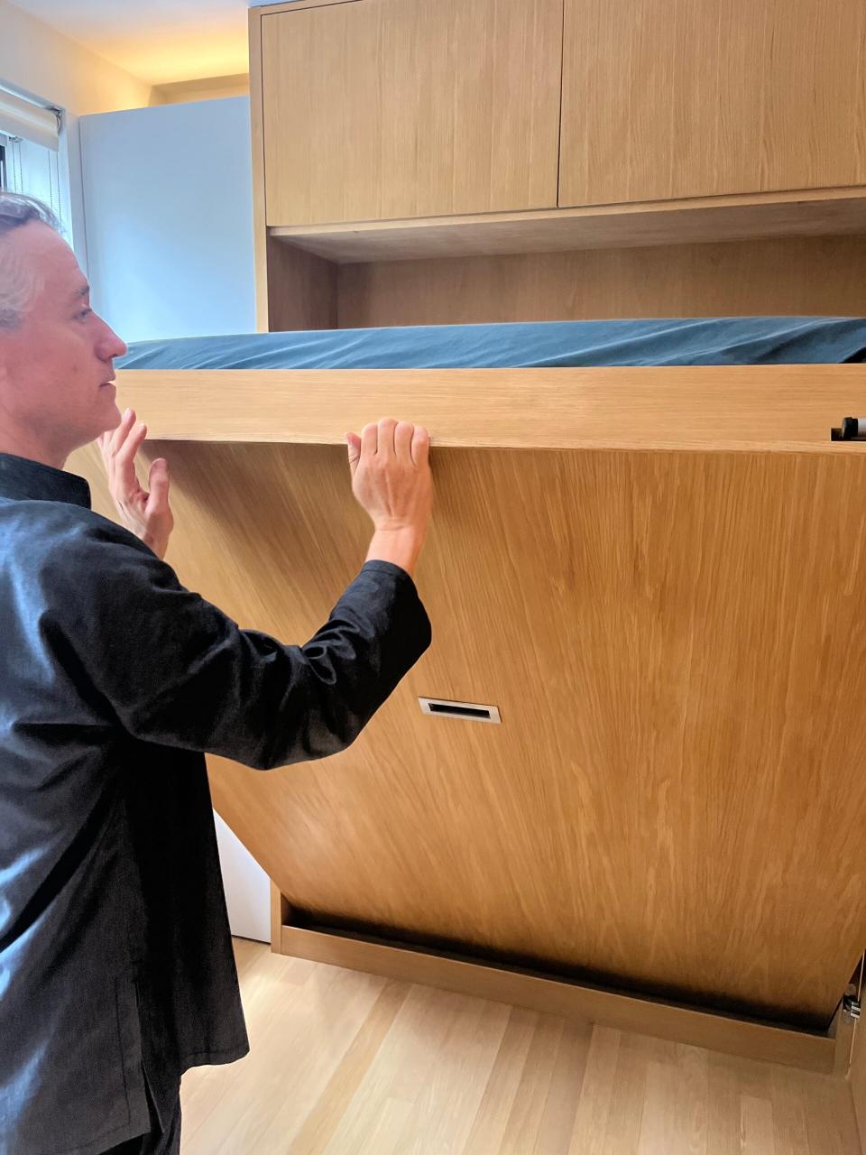 Robert Garneau lowers the Murphy bed down to the ground. 