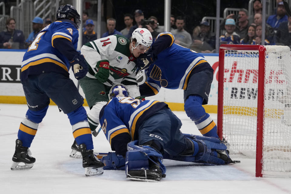 Minnesota Wild's Joel Eriksson Ek (14) scores past St. Louis Blues goaltender Jordan Binnington (50) as Blues' Nick Leddy (4) and Colton Parayko defend during the first period of an NHL hockey game Wednesday, March 15, 2023, in St. Louis. (AP Photo/Jeff Roberson)