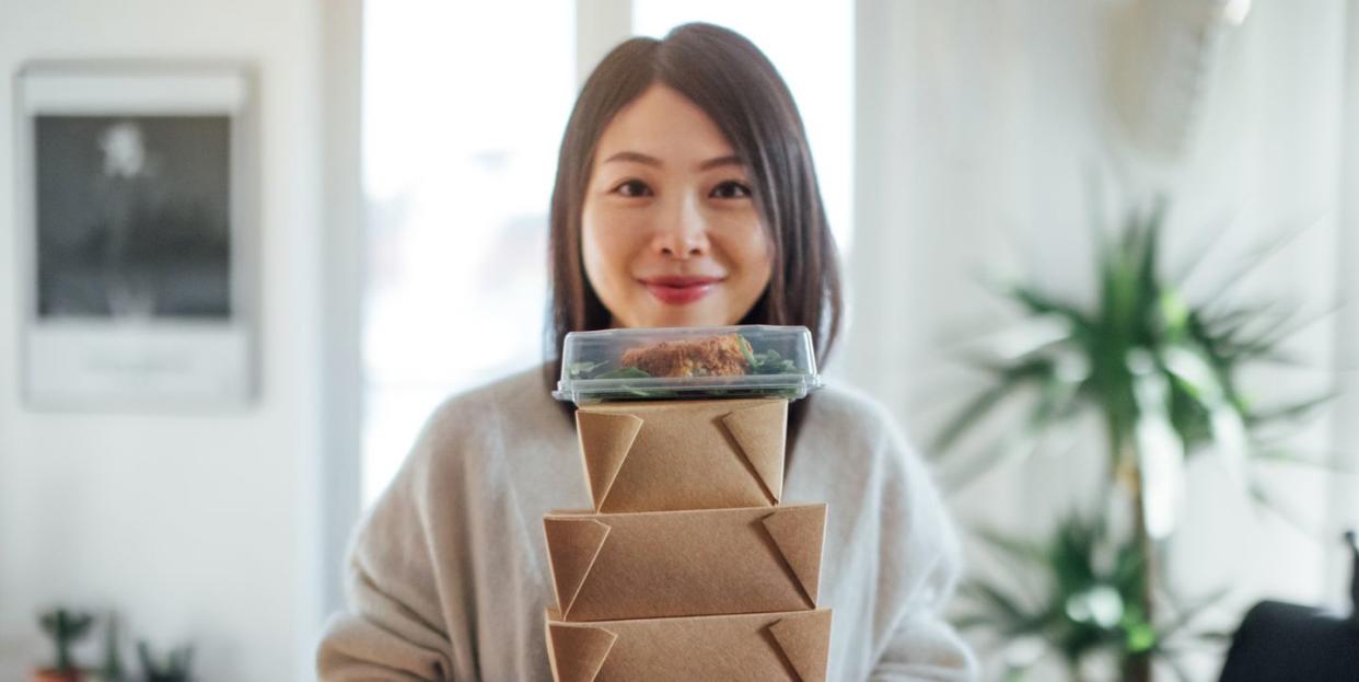 young woman carrying takeaway food boxes