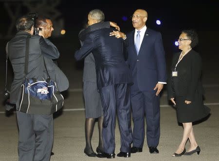 U.S. President Barack Obama (C, back to camera) gets a hug from Jamaica's Prime Minister Portia Simpson Miller as he arrives aboard Air Force One at Norman Manley International Airport in Kingston, Jamaica April 8, 2015. REUTERS/Jonathan Ernst