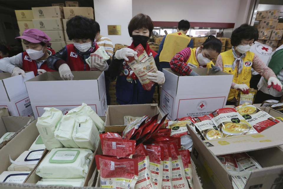 Trabajadores de la Cruz Roja preparan paquetes con productos básicos como comida instantánea para repartirlos entre gente en situación de necesidad durante la crisis del coronavirus, en las instalaciones de Cruz Roja surcoreana, en Seúl, Corea del Sur, el 27 de marzo de 2020. (AP Foto/Ahn Young-joon)