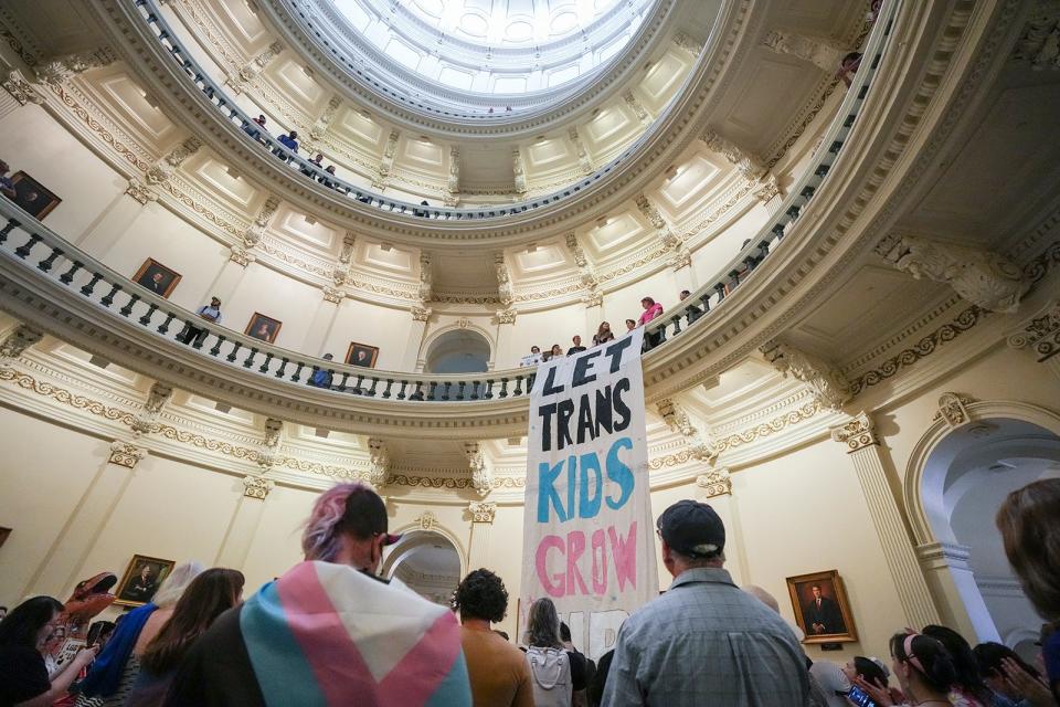 Equality Texas leadership unfurls a banner in the Capitol Rotunda reading "let trans kids grow up" as LGBTQ+ rights activists protest SB14 in May.