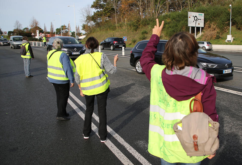 Demonstrators wearing their yellow vests wave to cars as they open the toll gates on motorway near Biarritz, southwestern France, Tuesday, Dec.4, 2018. French Prime Minister Edouard Philippe announced a suspension of fuel tax hikes Tuesday, a major U-turn in an effort to appease a protest movement that has radicalized and plunged Paris into chaos last weekend. (AP Photo/Bob Edme)