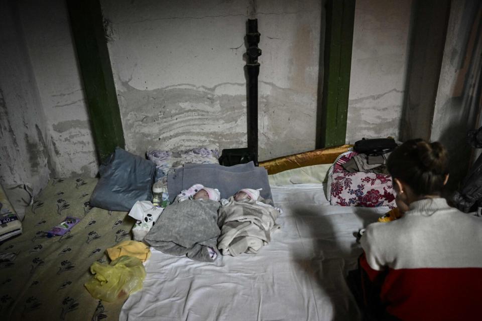 A woman sits with two babies being treated in a makeshift basement bomb shelter at a pediatrics hospital