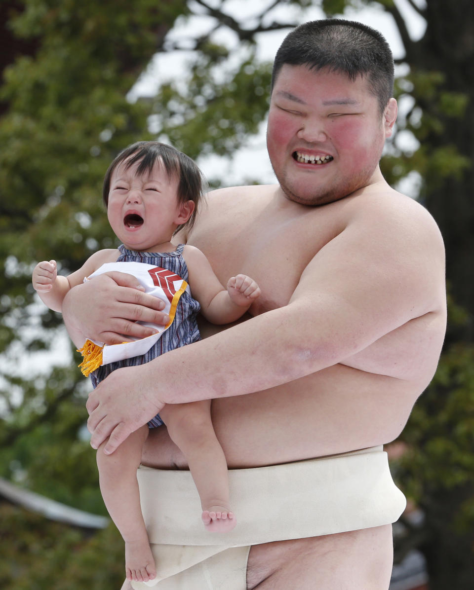 An unidentified baby, held by a college sumo wrester, cries during Naki Sumo, or Crying Baby Contest, as a judge looks on at Sensoji temple in Tokyo Monday, April 29, 2013. The babies born in 2012 participated in the annual traditional ritual performed as a prayer for their healthy growth.