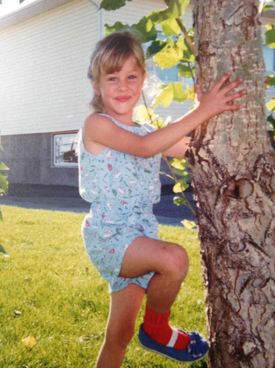 mackenzie porter as a child posing next to a tree