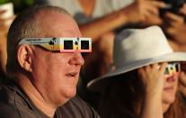 PALM COVE, AUSTRALIA - NOVEMBER 14: A spectator views the solar eclipse through special eclipse viewing glasses on November 14, 2012 in Palm Cove, Australia. Thousands of eclipse-watchers have gathered in part of North Queensland to enjoy the solar eclipse, the first in Australia in a decade. (Photo by Ian Hitchcock/Getty Images)